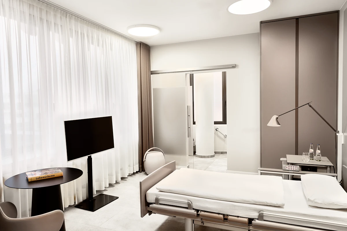 Modernes Patientenzimmer der RKM 740 Facharztklinik in Düsseldorf mit Einzelbett, TV, Tageslicht und integriertem Bad