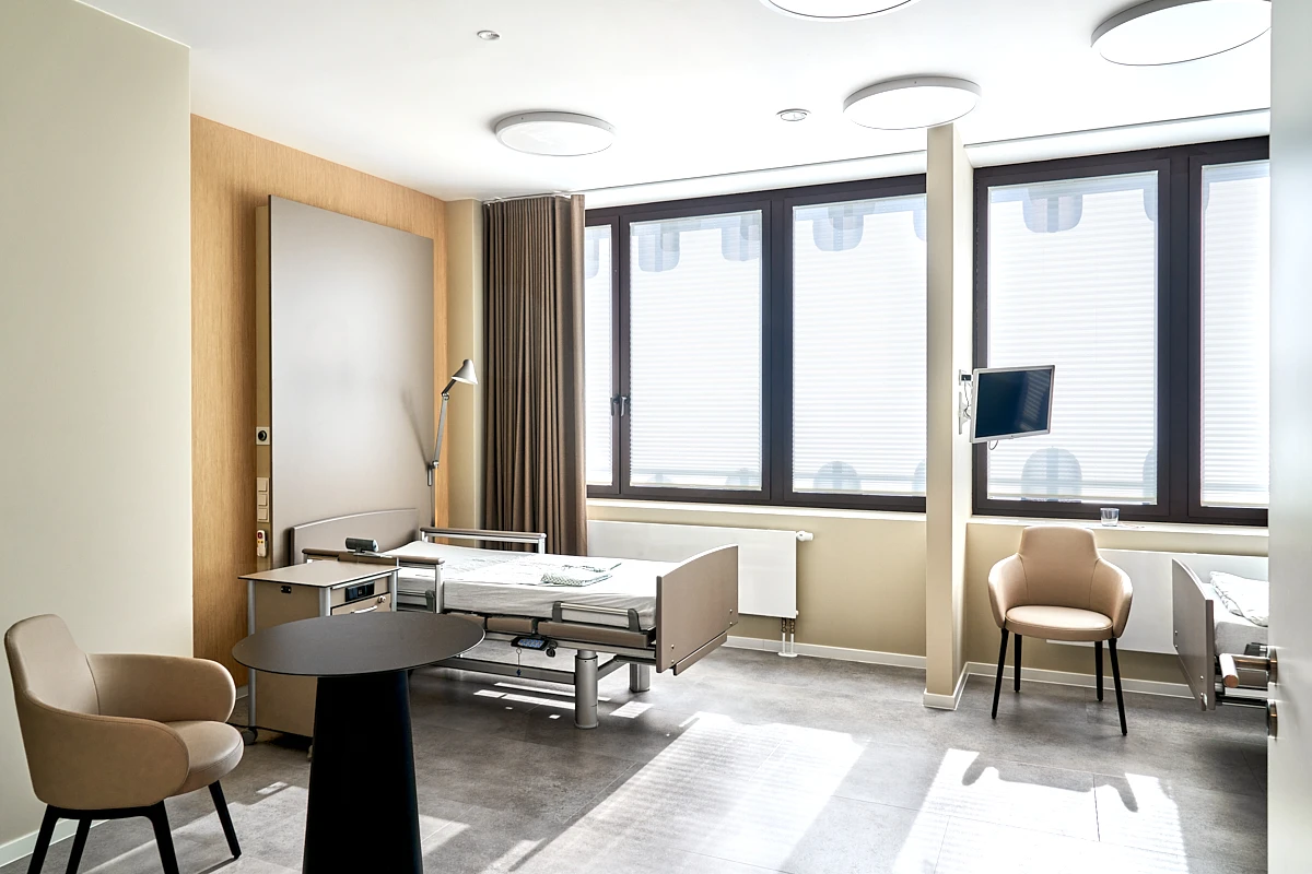 Helles Patientenzimmer der RKM 740 Facharztklinik in Düsseldorf mit zwei Betten, Sitzbereich und Monitor